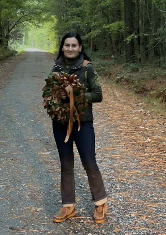 Holding a dried magnolia wreath on a wooded lane