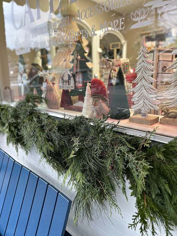Fresh evergreen garland along a shop window box above a blue bench
