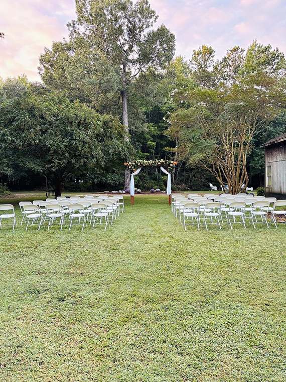 Ceremony setup with a garland arch and rows of white chairs