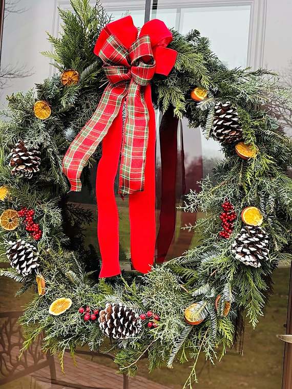Cedar & fir wreath with a red plaid bow, pinecones & dried oranges